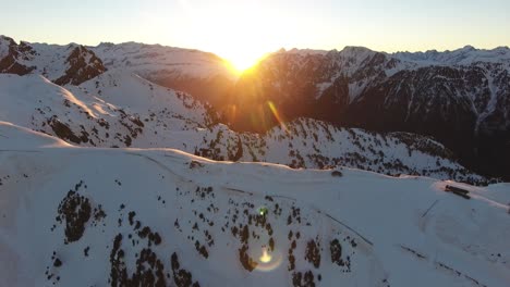 Chamrousse-French-alps-with-sunrise-between-the-peaks,-Aerial-flyover-approach-shot