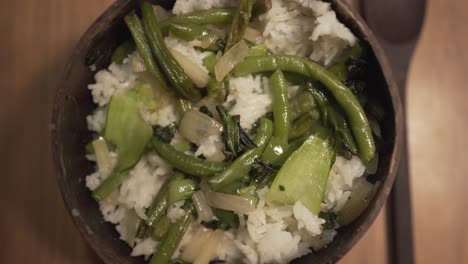 Amazing-coconut-bowl-dish-with-green-vegetables-onion-beans-and-white-rice-served-on-a-table-with-wooden-spoon