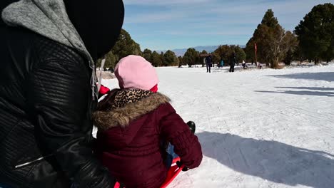 Woman-pushing-girl-on-sled-down-a-hill-at-Lee-Canyon-Recreation-Area