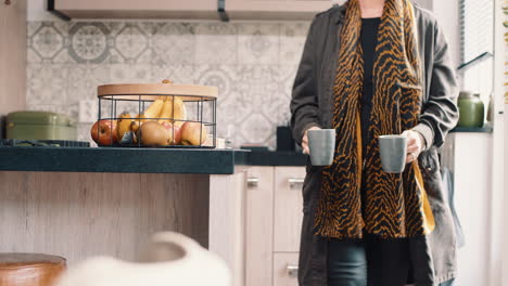 Woman-walking-from-the-kitchen-with-2-cups-of-coffee-in-her-hand-towards-the-living-room