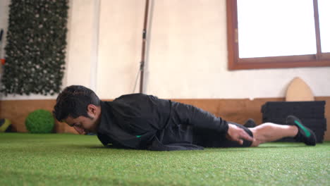 muscular-person-performing-lower-back-exercise-on-artificial-grass