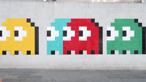 Fußgänger-Gehen-An-Einem-Wall-Street-Kunstwerk-Vorbei,-Das-Das-Klassische-Arcade-Spiel-Pac-Man-In-Hongkong-Darstellt