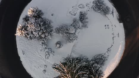 Rising-from-snow-covered-inner-circle-of-roundabout-in-winter-time,-aerial