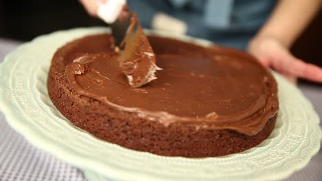 Eine-Schokoladenglasurfüllung-Auf-Die-Erste-Schicht-Eines-Selbstgemachten-Kuchens-Streichen
