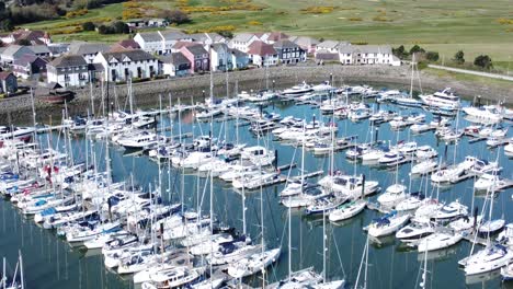 Flying-above-luxury-yachts-and-sailboats-reflections-on-sunny-Conwy-marina-birdseye-aerial-view-rise-forwards