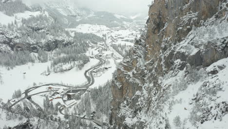 Aerial-of-snow-covered-mountain-ridge-with-a-small-Swiss-town-in-the-background