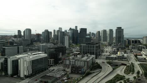 Dull-grey-skies-backlight-metropolitan-downtown-Seattle,-Washington,-aerial-push