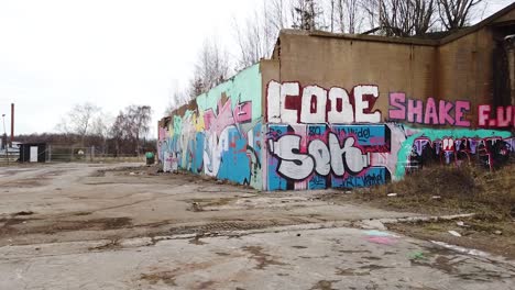 Graffiti-wall-art-in-old-paper-mill-ruins-in-Vargön,-Sweden,-wide-spinning-shot