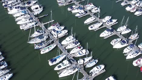 Flying-above-luxury-yachts-and-sailboats-reflections-on-sunny-Conwy-marina-birdseye-aerial-orbit-right-view
