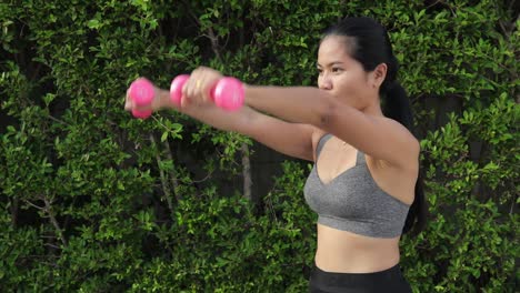 Sportliche-Thailänderin-Trainiert-Mit-Hanteln-Und-Streckt-Die-Arme-Nach-Vorne-Und-Seitwärts