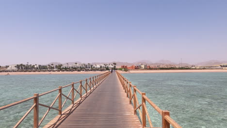 Wooden-jetty-bridge-above-turquoise-tropical-sea,-Sharm-El-Sheikh,-pan