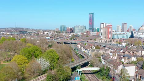 Drone-shot-towards-central-Croydon-passing-over-green-tram
