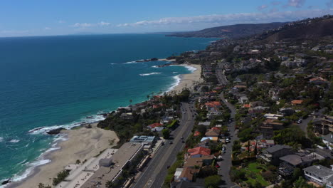 Aerial-drone-footage-traveling-high-above-a-coastal-beach-community-along-Pacific-Coast-highway-Route-1-in-Southern-California-on-a-bright-sunny-day