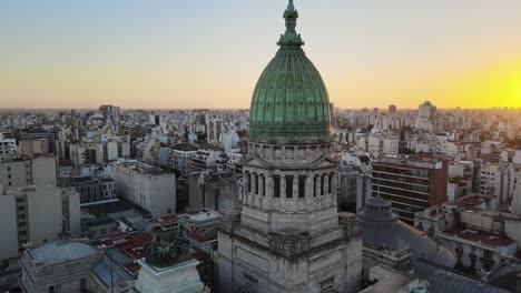 Aerial-flying-above-Argentine-Congress-palace-green-bronze-dome-surrounded-by-Buenos-Aires-buildings-at-golden-hour