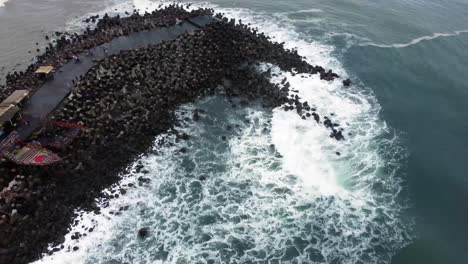 Aerial-view-of-sea-wave-crashing-tetra-concrete-block-or-wave-breaker-stone-at-Glagah-beach,-Yogyakarta