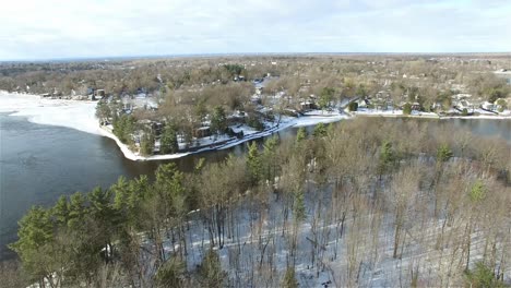 Sliding-Drone-shot-of-summer-and-winter-houses-surrounding-a-lake