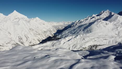 Bei-Sonnigem-Wetter-In-Den-Schweizer-Alpen-Kommt-Per-Drohne-Ein-Wenig-Nebel-Aus-Dem-Tal-In-Die-Schneebedeckten-Berge
