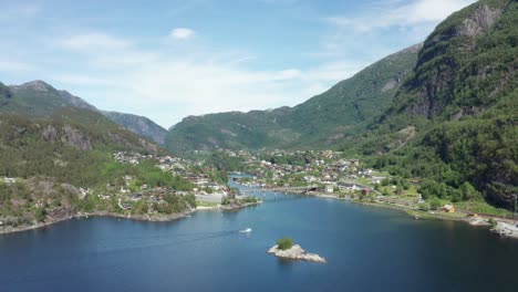 A-boat-passing-Sorfjorden-at-Stanghelle---Idyllic-village-in-Vaksdal---Sideways-moving-ascending-aerial-overview
