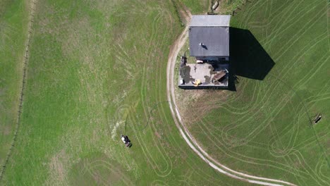 Swiss-farmer-spraying-fertilizer-on-his-field-in-the-hills,-aerial-view
