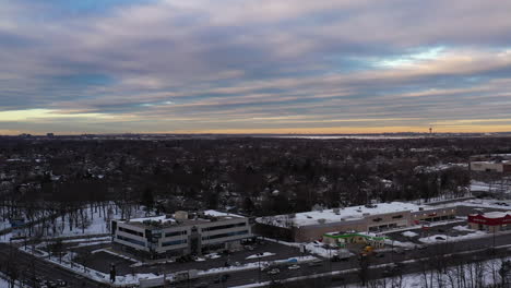 An-aerial-drone-shot-over-a-suburban-neighborhood-during-a-cloudy-but-golden-sunrise,-taken-after-a-snow-storm