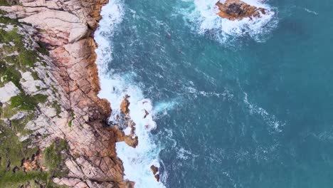 Aerial-Top-View-Drone-Footage-of-Ocean-Waves-Reaching-Green-Shore