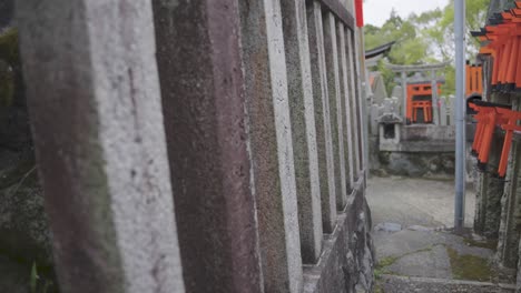 Santuario-Fushimi-Inari,-Empuje-Cercano-A-Lo-Largo-De-La-Cerca-De-Piedra-Del-Templo,-Kyoto-Japón