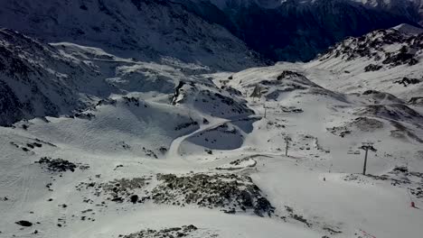 View-of-Cable-car-funitels-scattered-across-barren-snowy-landscape-in-Val-Thorens,-French-Alps---Aerial-Fly-over-shot
