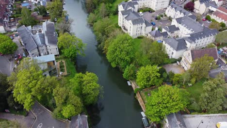Top-down-aerial-over-the-river-Avon-in-Bath,-a-variety-of-residential-buildings-and-communal-areas-are-on-the-riverside