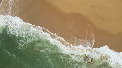 4K-aerial-view-of-the-waves-crushing-in-a-yellow-sand-beach