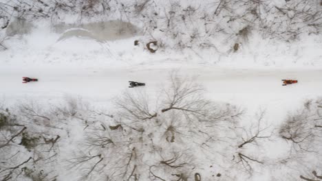 Snowmobiles-driving-along-snow-covered-road-Aerial-top-down-tracking-shot