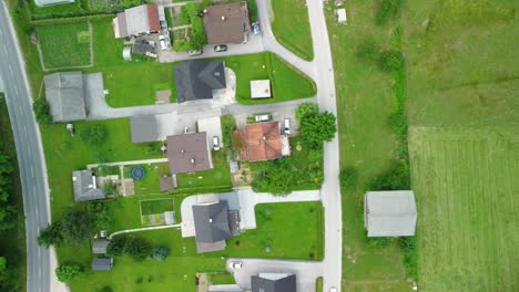 Flug-über-Eine-Kleine-Siedlung-Mit-Mittelgroßen-Einfamilienhäusern-Zwischen-Grünen-Wiesen