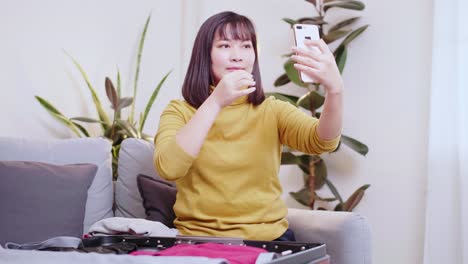 Mujer-Asiática-Tomando-Selfie-Mientras-Se-Prepara-Para-Viajar