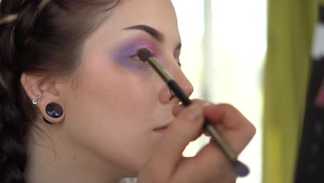 Applying-eye-shadow-of-a-purple-color-in-close-up