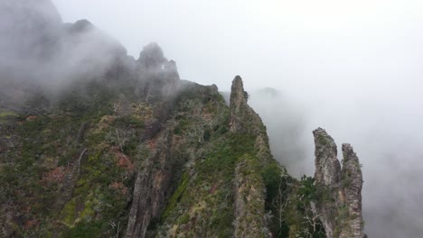 Drone-shot-of-Nuns-Valley-in-Madeira,-moving-sideways-along-the-sharp-and-pointy-peaks-among-the-thin-and-spooky-clouds