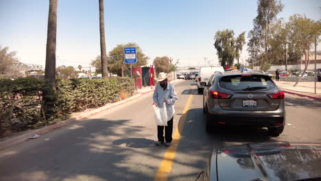 Old-Beggar-Standing-In-The-Middle-Of-The-Street-Amidst-Danger-And-Traffic-At-The-Border-Crossing-In-Tijuana,-Mexico