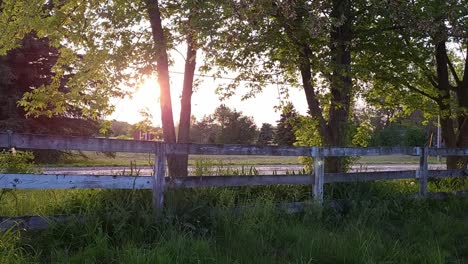 Old-Wooden-Fence-In-Countryside-Field-With-Maple-Trees-Backlit-With-Sunlight-In-Southeast-Michigan,-USA