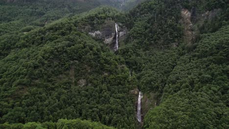 Two-big-waterfalls-in-the-woods-in-Switzerland,-aerial-forward-flight