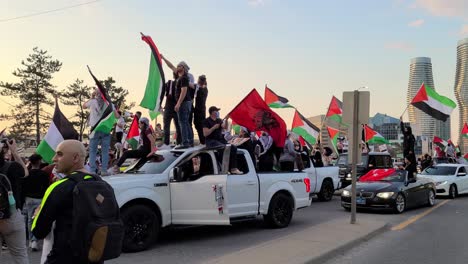 Free-Palestine-protesters-rally,-standing-on-cars-waving-Palestine-flags-and-chanting-support-during-Israel-conflict