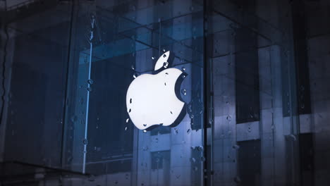Apple-Store-logo-banner-through-window,-showcase,-rain-dropping,-rainy-day,-retail-store-front,-popular-computer-brand-store,-looping-background-raindrop