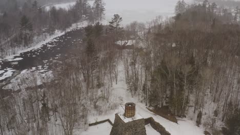 Katahdin-Ironworks-by-Pleasant-River-in-Maine-Winter-snowfall-Aerial-tilt-reveal