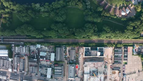 top-down-drone-shot-of-train-passing-between-nature-and-built-up-scrap-yard