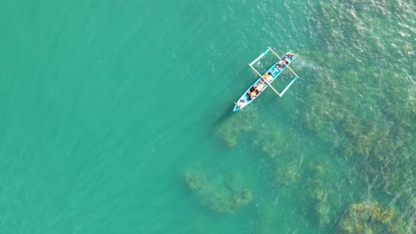 Small-boat-in-turquoise-tropical-bay,-Gesing-Beach,-Indonesia,-aerial-panorama