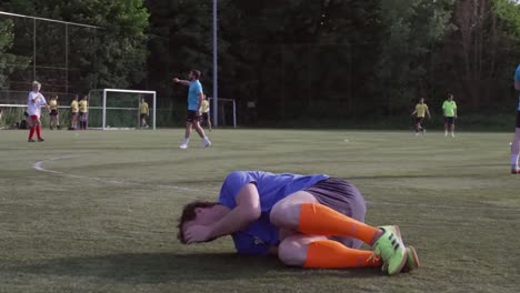 Soccer-player-gets-kicked-in-the-balls-by-the-football-on-the-pitch-and-falls-down-in-pain