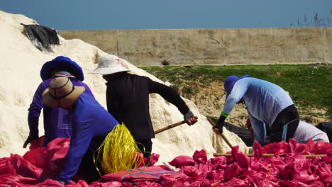 Close-up-of-workers-at-foot-of-a-salt-mountain-to-fill-bags-for-salt-mines