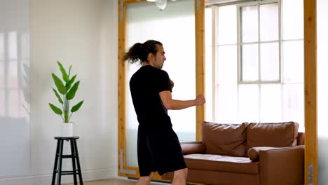 Latino-Man-with-Ponytail-and-Goatee-Performing-Taekwondo-Axe-Kicks-Back-and-Forth-in-Home