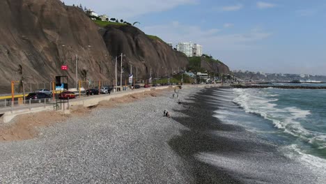 4k-daytime-aerial-video-flying-over-the-cobblestone-beach-of-Miraflores-in-Lima,-Peru-in-a-sunny-summer-day