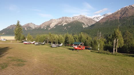 Aerial-footage-rotating-around-airplanes-parked-along-a-grass-airstrip-in-the-Talkeetna-Range-of-Alaska