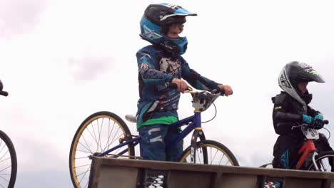 Junge-Radfahrer-Mit-Schutzhelmen-Stehen-An-Der-Startlinie-Einer-BMX-Rennstrecke