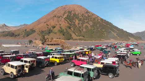 Jeeps-parked-in-Sea-of-Sand-in-Java-with-Mount-Batok-in-background,-aerial