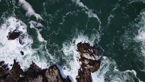 Aerial---Rough-water-leaving-beautiful-patterns-along-rocky-coastline,-top-down-shot,-flying-horizontal